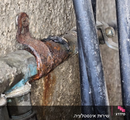 צינור חלוד עם נזילה על קיר בטון